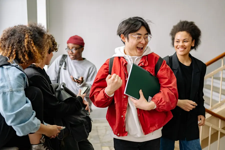 Four students talking together on a staircase between classes