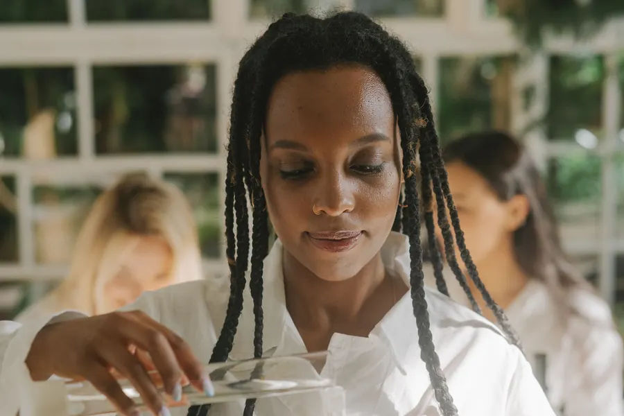 A student in a white coat holding petri dishes in a laboratory